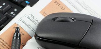na obrazku jest czarna myszka komputerowa, długopis, leżą na kartkach papieru z oznaczeniami PIT