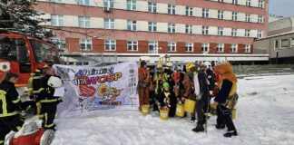 od lewej strażacy, baner wielkiej orkiestry świątecznej pomocy, dalej alpiniści przebrani za postacie z bajek, w tle znajduje się budynek uniwersyteckiego dziecięcego szpitala klinicznego.