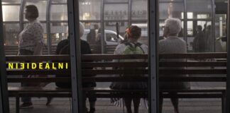 osoby siedzące plecami na przystanku autobusowym w lewej stronie zdjęcia widnieje żółty napis nieidealni