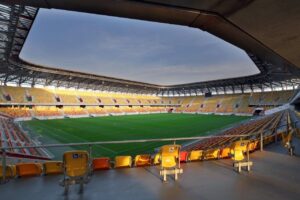 zdjęcie przedstawia pusty stadion, na pierwszym panie są trzy krzesełka z logiem osób niepełnosprawnych