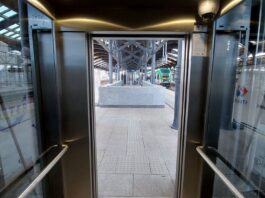 na zdjęciu znajduje sie winda od wewnątrz z perspektywy pierwszoosobowej z widokiem na stacje