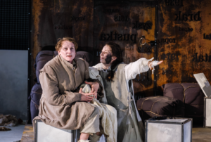 Scena ze spektaklu „Matka Courage i jej dzieci” w Teatrze Dramatycznym im. Aleksandra Węgierki w Białymstoku. Dwie aktorki w kostiumach siedzą na scenie, a jedna z nich wyciąga rękę w dramatycznym geście.