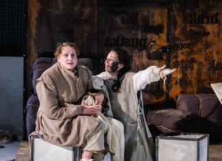 Scena ze spektaklu „Matka Courage i jej dzieci” w Teatrze Dramatycznym im. Aleksandra Węgierki w Białymstoku. Dwie aktorki w kostiumach siedzą na scenie, a jedna z nich wyciąga rękę w dramatycznym geście.